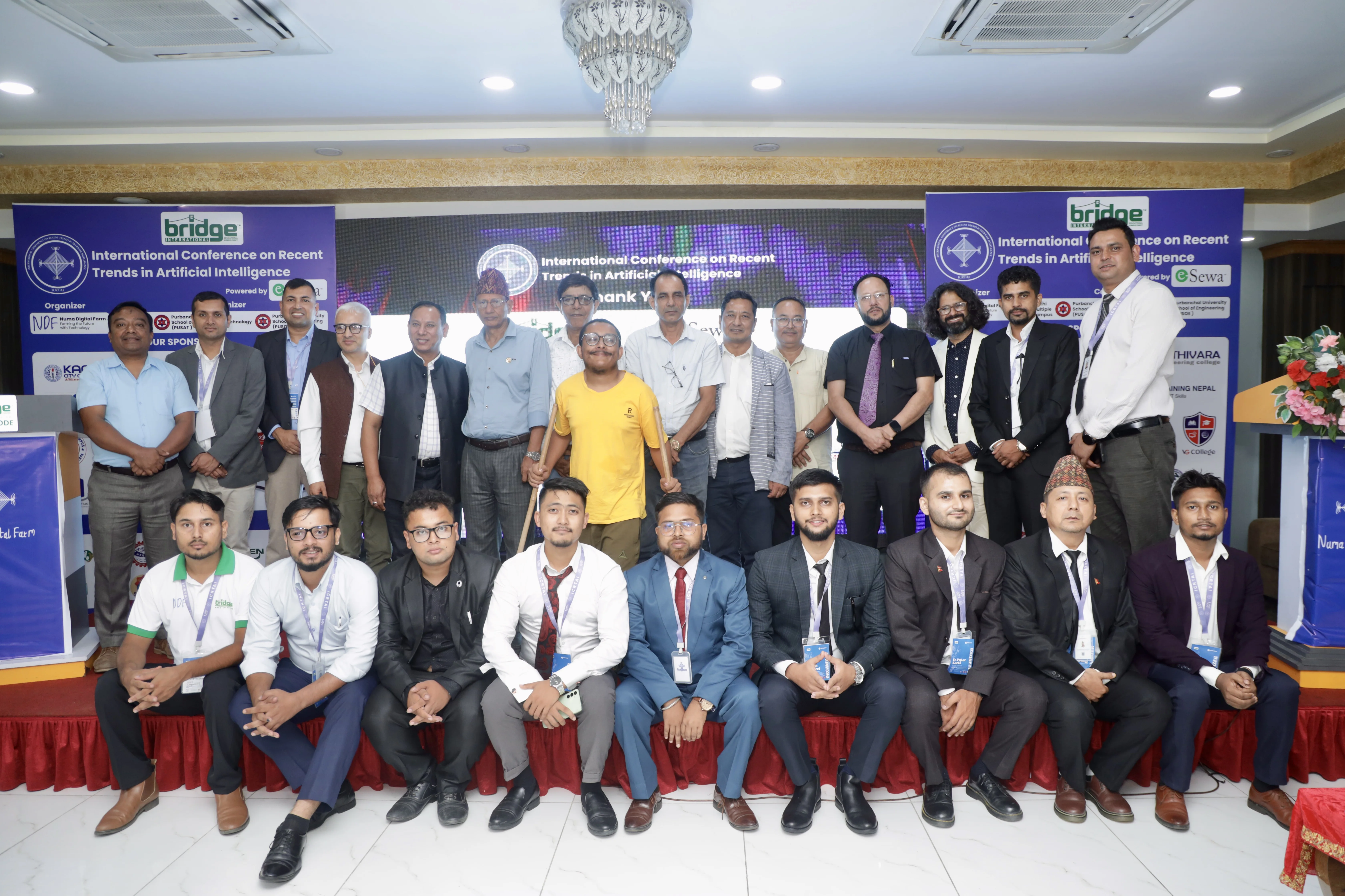 Group photo on the ICRTAI conference stage in front of event branding and display screens.